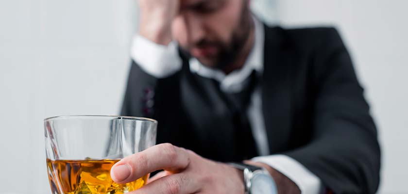 грустный мужчина со стаканом алкоголя