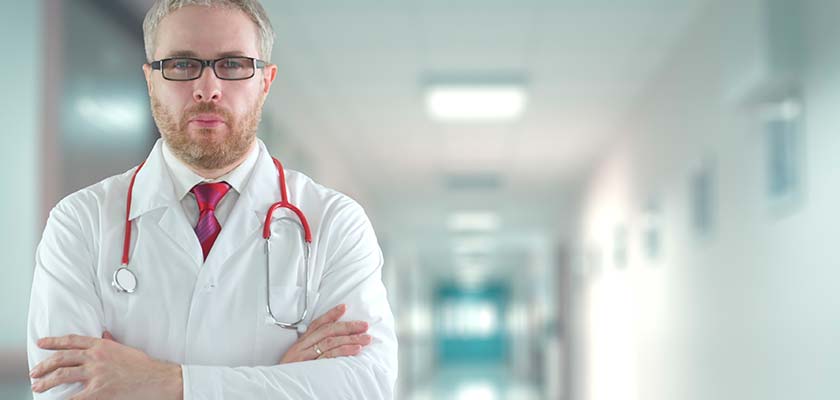 мужчина врач стоит в больничном коридоре и смотрит в камеру