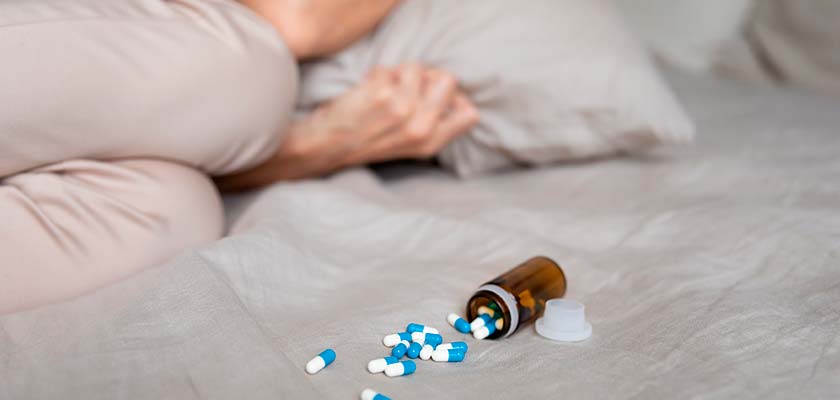 женщина лежит на кровати рядом с таблетками