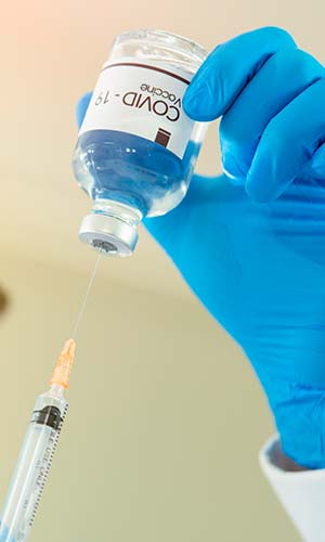 врач набирает в шприц вакцину из ампулы